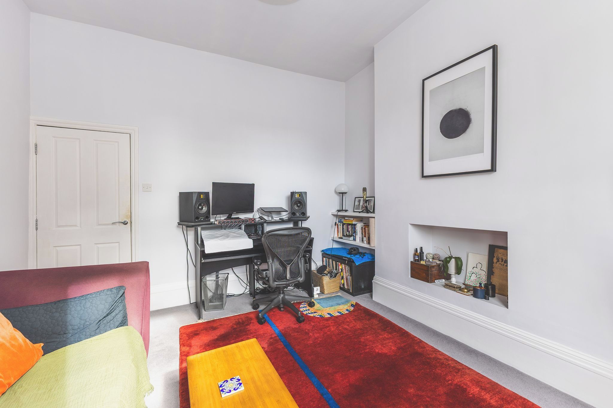 A room with a desk, computer, speakers, and a bookshelf.