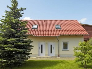 Ein zweistöckiges Gebäude mit rotem Ziegeldach, zwei Türen und einem kleinen Fenster im oberen Stockwerk.