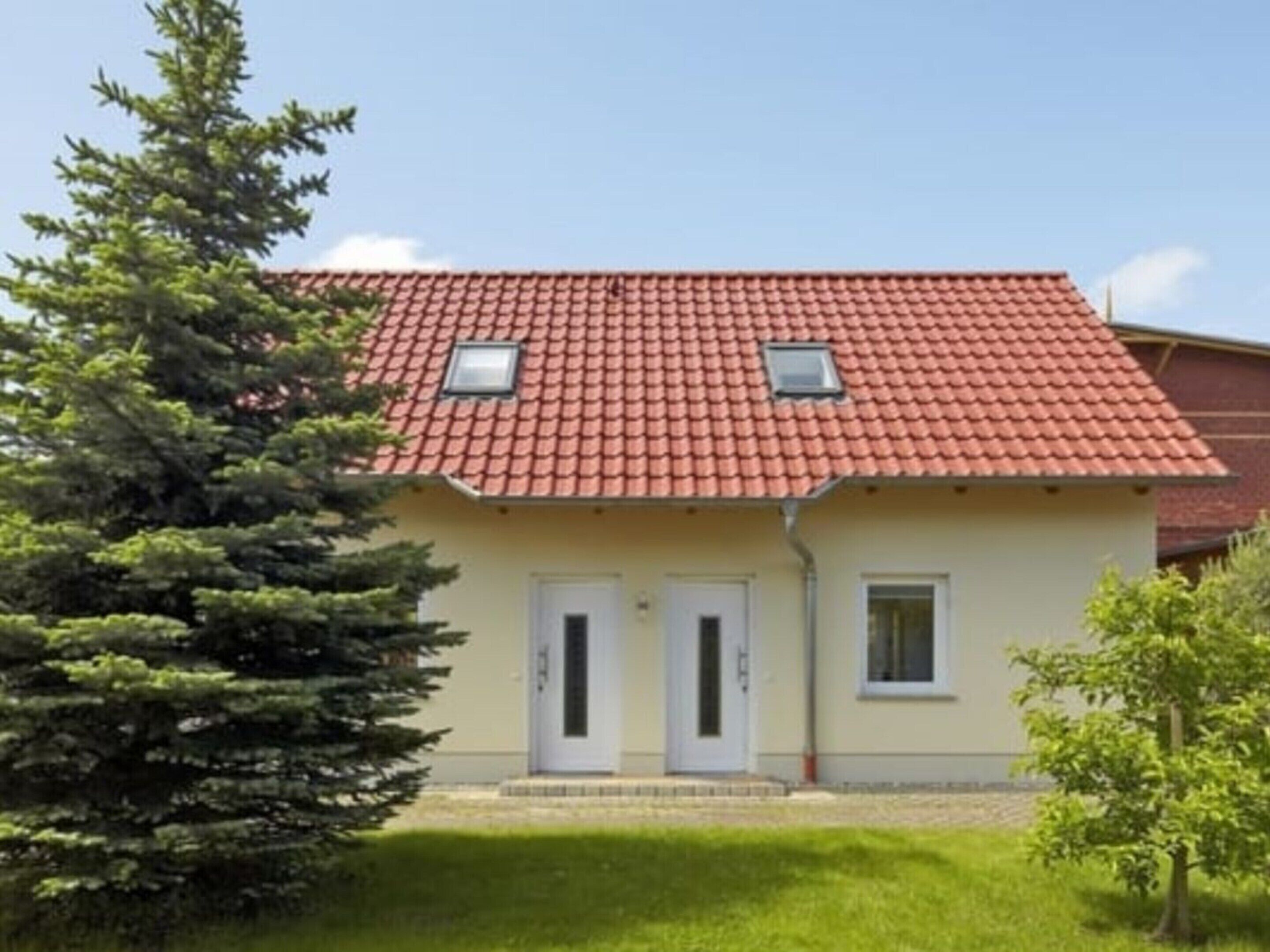 Ein zweistöckiges Gebäude mit roten Ziegeln, zwei weißen Türen und einem kleinen Fenster im Obergeschoss.