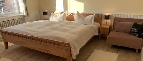 Un dormitorio con cama de madera, mesitas de noche y una silla.
