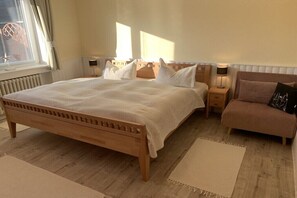 A bedroom with a wooden bed, bedside tables, a nightstand, and a chair. - Dike warden - Directly in Wyk (Wyk\/Föhr)