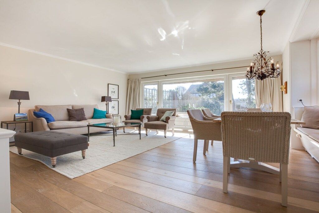 Amplia sala de estar con un conjunto de sofá, reposapiés y sillones de mimbre.