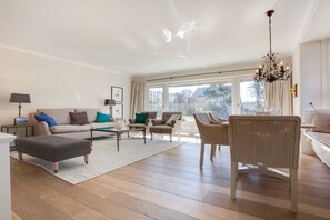 A spacious living room with a sofa set, ottoman, and wicker chairs. - Holiday home with 3 bedrooms (Wenningstedt-Braderup)