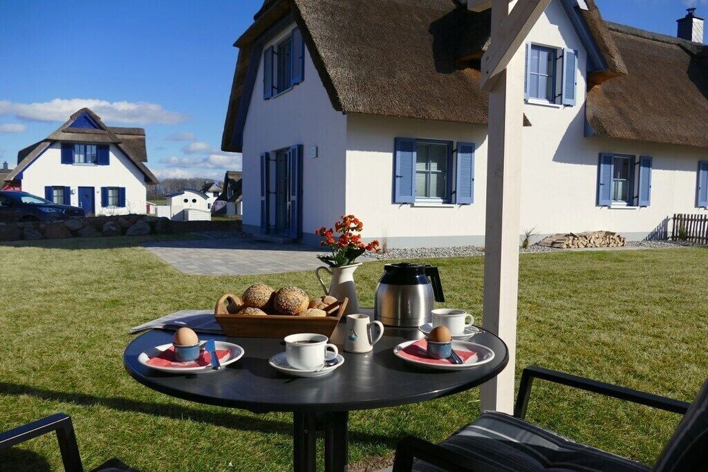 A table set outdoors with breakfast items, a coffee pot, and a flower vase.