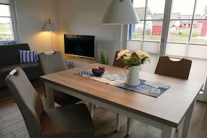 Ein Essbereich mit Tisch, Stühlen, einem Fernseher und einem Fenster mit Blick.