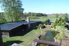 A house with a pond, a wooden deck, and a grassy yard. - Holiday home Rosenbrock (Undeloh)
