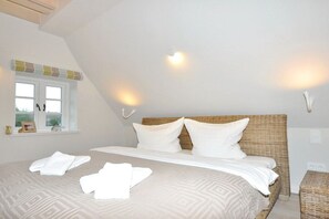 Une chambre à coucher avec un grand lit, deux lampes de chevet, une fenêtre avec des rideaux et une table de chevet avec une lampe.