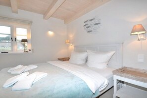 Ein Schlafzimmer mit einem Bett, Kissen, einem Nachttisch, einer Lampe und einer Wanddekoration.