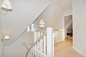 A staircase with white railings and pendant lighting. - Holiday home with 3 bedrooms (Sankt Peter Ording)