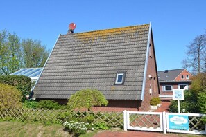 A house with a sloped roof, a small window, and a satellite dish. - Holiday home Wolkenblick (Wittmund - Harlesiel)