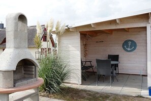 A patio area with a stone oven, outdoor seating, and a decorative anchor sign. - Thatched house "Melsa" (Zierow)