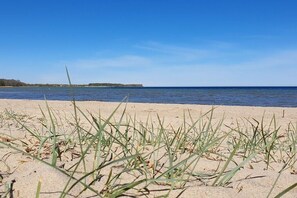 A beach with sand and grass in the foreground and a body of water in the background. - Thatched house "Melsa" (Zierow)