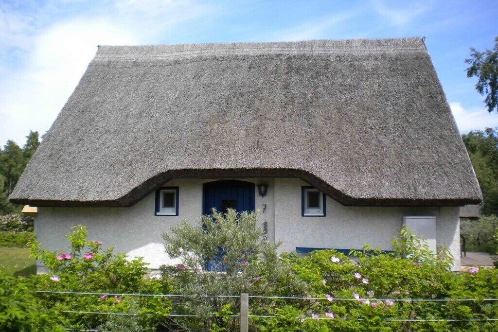 A traditional thatched-roof house with a small porch and a blue door.