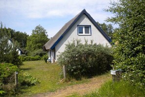 A single-story house with a gabled roof, a visible window, and a pathway leading to the entrance. - Thatched-roof house on Hiddensee (Seebad Hiddensee)