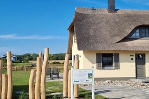 A traditional thatched-roof house with a stone pathway leading to the entrance. - Thatched house "MOOI" (Zierow)