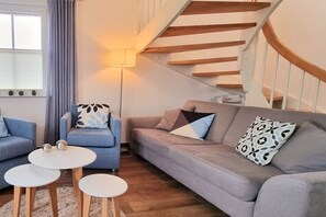 A living room with a sofa, two armchairs, a coffee table, and a staircase. - Thatched house "MOOI" (Zierow)