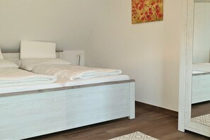 A bed with a white headboard and footboard, a bedside table, and a mirror on the wall. - Thatched house "MOOI" (Zierow)