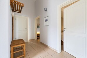 A hallway with white doors, a wooden bench, and a framed picture on the wall. - Holiday home in Bohnert with swimming pool (Bohnert)