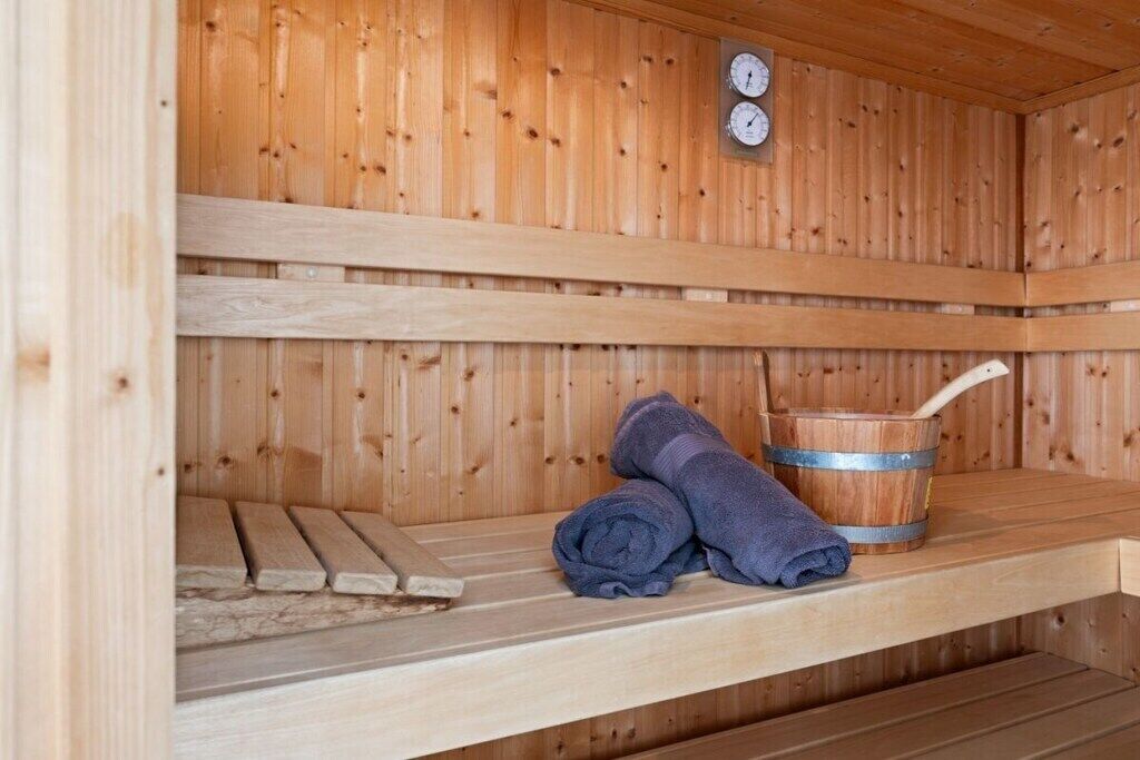 Una sauna de madera con un banco, un cubo y toallas.