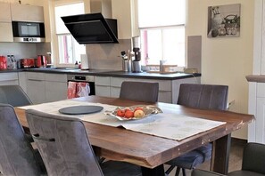 A modern kitchen with a dining table set for two, featuring a microwave, coffee maker, and various kitchen appliances. - Thatched house "Hemmer's Hus" (Zierow)