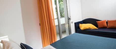 Una habitación de hotel con cama, sofá, puerta corrediza de vidrio y cortina.