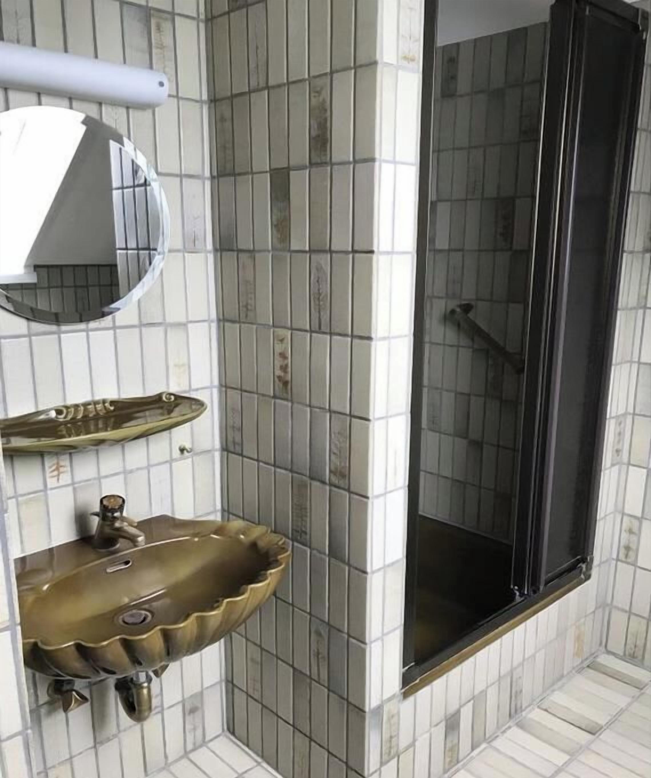 Um banheiro com pia, espelho e box de chuveiro.