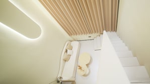 Una escalera moderna con un diseño minimalista, que presenta un pasamanos blanco y un suelo de color claro.