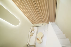 Una escalera moderna con un diseño minimalista, que presenta un pasamanos blanco y un suelo de color claro.