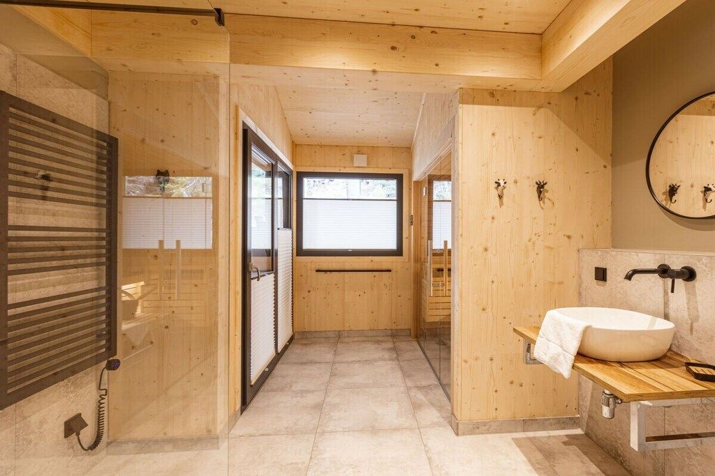 Un interno in legno con un bagno dotato di un lavandino ampio e uno specchio.