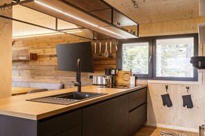 Eine moderne Küche mit Holzelementen, einem schwarzen Spülbecken und hängenden Küchenutensilien.