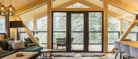 A spacious loft-style room with a high ceiling, large windows, and a cozy seating area.