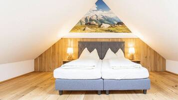 Ein Schlafzimmer mit Holzbalkendecke, einem Bett mit Kissen und zwei Nachttischlampen.