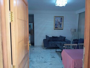 A living room with a sofa, a table, and a chair. There is a painting on the wall and a lamp. - A furnished apartment in Cité Ennasr, located on a private floor with no neighbors. (Ariana)