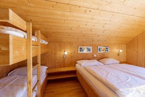 Ein Zimmer in einer Holzhütte mit Etagenbetten, einem Einzelbett und zwei Wandleuchten.
