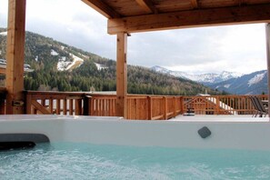 A hot tub with a wooden deck and a mountain view. - Cabin in Hohentauern with sauna (Hohentauern)