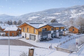 A modern building with a wooden facade and large windows, surrounded by snow-covered hills. - Apartment with 1 bedroom (St. Georgen am Kreischberg)