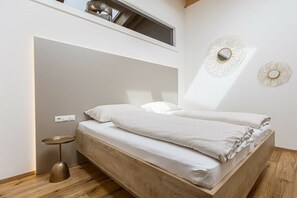 Une chambre à coucher avec un lit en bois, une petite table ronde et deux miroirs décoratifs fixés au mur.