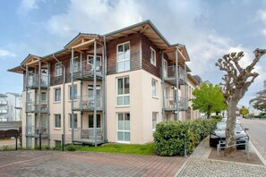 A multi-story residential building with balconies, a paved driveway, and a parked car. - Apartment building Linquenda 14 (Ahlbeck (Seebad))