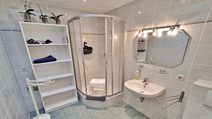 Un bany modern amb plat de dutxa de vidre, un lavabo blanc i un mirall.