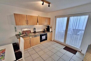 Una cocina con armarios de madera, un lavamanos, una estufa y una ventana con cortinas.