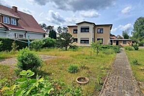 A residential area with a paved pathway leading to a house with a red roof and a two-story building with a beige facade. - Holiday apartment Seahorse (Ahlbeck (Seebad))