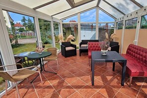 A conservatory with a glass roof, furnished with a table, chairs, and a sofa. - Holiday apartment Seahorse (Ahlbeck (Seebad))