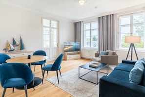 Un salon moderne comprenant un téléviseur, un canapé, des fauteuils et un coin repas.