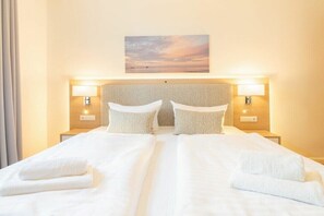 Un letto matrimoniale con una testiera, due abat-jour e un quadro appeso sopra.