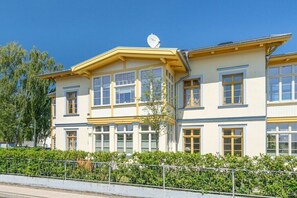 Un immeuble à plusieurs étages, doté d’une façade jaune, de grandes fenêtres et d’une antenne parabolique sur le toit.
