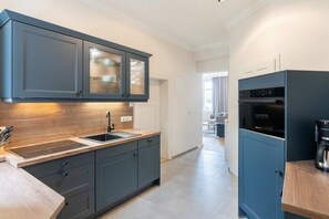Une cuisine moderne avec des meubles de rangement aux couleurs foncées, un plan de travail en bois et un four encastré.