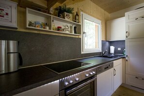A modern kitchen with a built-in stove, oven, and a coffee maker on the counter. - Cabin with 1 bedroom (St. Georgen am Kreischberg)