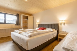 A bedroom with a bed, bedside tables, a window, and a wooden ceiling. - Apartment with 1 bedroom (St. Georgen am Kreischberg)