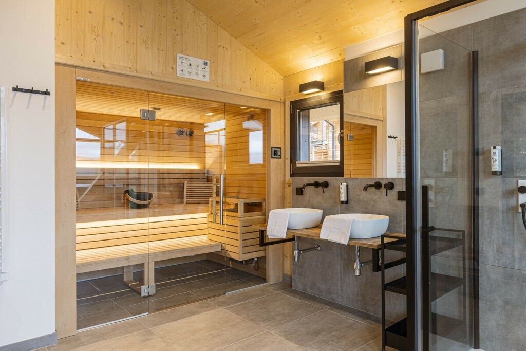 A modern bathroom with wooden paneling, a glass shower enclosure, and a dual sink vanity.