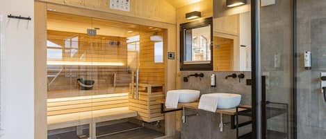 A modern bathroom with wooden paneling, a glass shower enclosure, and a dual sink vanity.